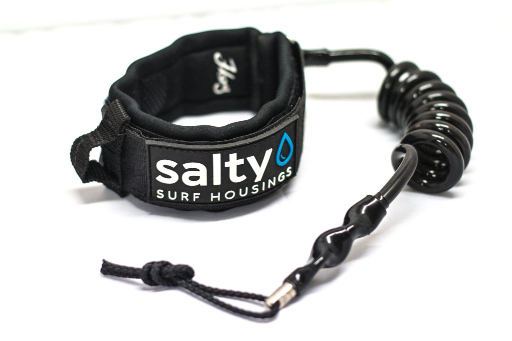 Black surf bicep leash by Salty Surf Housings featuring a padded neoprene armband and a coiled urethane cord.